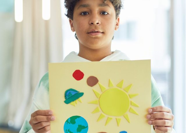 A student proudly holding up a project they created